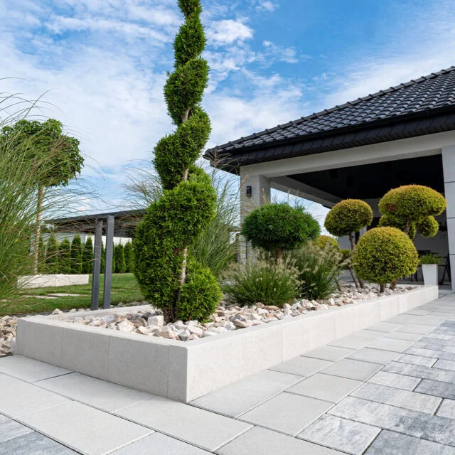 Połączenie płyt brukowych z naturalnym drewnem w ogrodzie